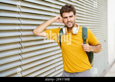 Ritratto di giovane uomo con cuffie in stile urbano. Giovane uomo con cuffie in stile urbano Foto Stock