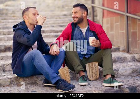 Una coppia gay che ha un pasto da portare via sulla strada. Concetto di relazione omosessuale.. Una coppia gay che ha un pasto da portare via sulla strada Foto Stock