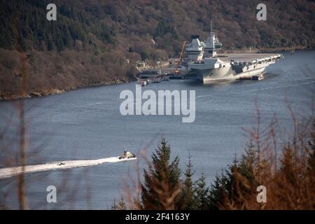 Finnart, Loch Long, Scozia, Regno Unito. 18 marzo 2021. NELLA FOTO: La polizia pattuglia barca con Royal Navy costole visto fare esercizi sul Loch lungo fare forme in acqua. HMS Queen Elizabeth è la più grande e più avanzata nave da guerra mai costruita per la Royal Navy. Sia la regina Elisabetta della HMS (nella foto) che il principe del Galles della HMS sono le bandiere della nazione che pesano in 65,000 tonnellate e misurano 280 metri di lunghezza. Credit: Colin Fisher/Alamy Live News. Foto Stock