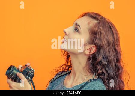 Pessive Hipster Girl Photographer cercando con Vintage Film Camera in mano cercare di fing qualsiasi cosa insolita per scattare foto, CopySpace. Hipster Girl Photographer cercando con Vintage Film Camera nelle sue mani cercare di fing qualsiasi cosa insolita per scattare foto, CopySpace Foto Stock