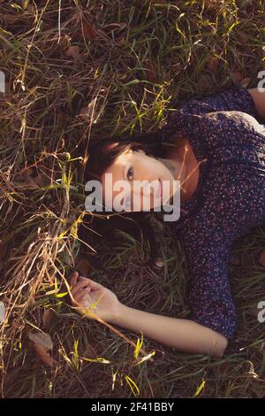 Calma ragazza in sdraiata in erba alta nei campi, copyspace in cima Foto Stock