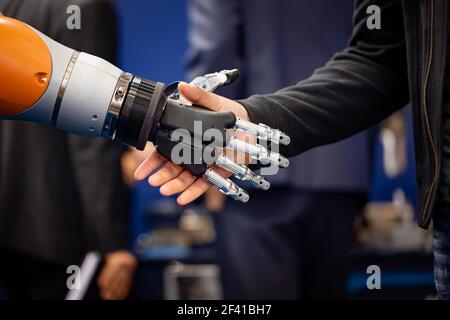 La mano di un uomo d'affari che stringono le mani con un robot androide. Il concetto di interazione umana con intelligenza artificiale. Foto Stock