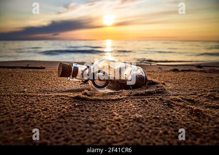 Messaggio in bottiglia contro il sole che tramonta verso il basso Foto Stock