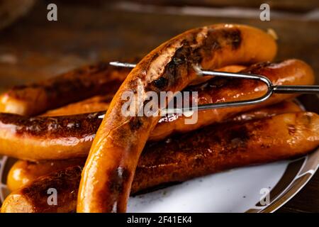 Salsicce alla griglia sul pannello di legno Foto Stock