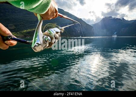 Donna che pesca sulla canna da pesca che gira in Norvegia. La pesca in Norvegia è un modo per abbracciare lo stile di vita locale. Innumerevoli laghi e fiumi e una costa estesa significa opportunità eccezionali... Foto Stock