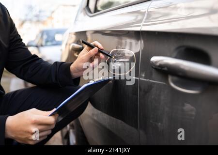 Agente assicurativo o regolatore ispettendo l'automobile dopo l'incidente Foto Stock