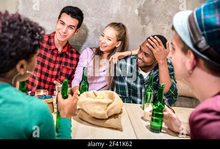 Gruppo di amici milleniali che beve birra in bottiglia e si diverte a. Il ristorante del cocktail bar alla moda offre un felice concetto di amicizia multirazziale Foto Stock