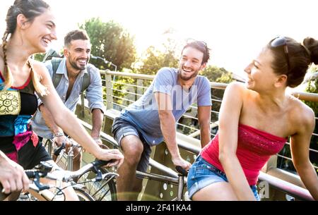 Felici amici milleniali che si divertono a cavallo in bicicletta nel parco cittadino - concetto di amicizia con studenti giovani millenari che si mettono in bicicletta insieme Foto Stock