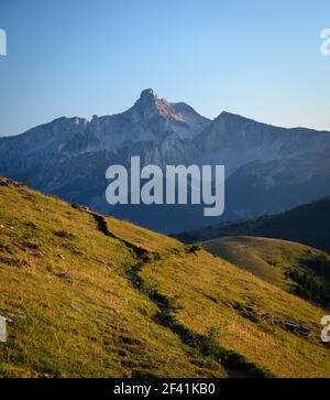 Percorso di montagna selvaggio con erba con montagna ripida in lo sfondo Foto Stock