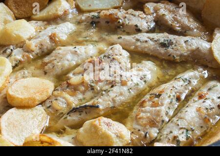 Primo piano di filetti di pollo con aglio e spezie in una salsa verde accompagnata da patate al forno. Cibo sano. Foto Stock