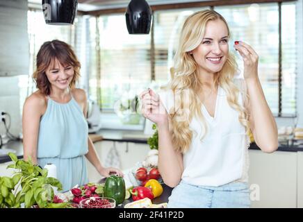 Due allegre amiche che si rilassano nella luminosa cucina Foto Stock