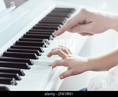 Primo piano immagine di due mani di madre e figlia suonare il pianoforte Foto Stock