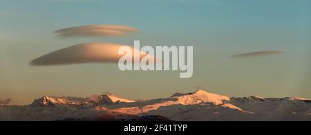 Grandi nuvole lenticolari bianche sulla Sierra Nevada (Spagna) al tramonto Foto Stock