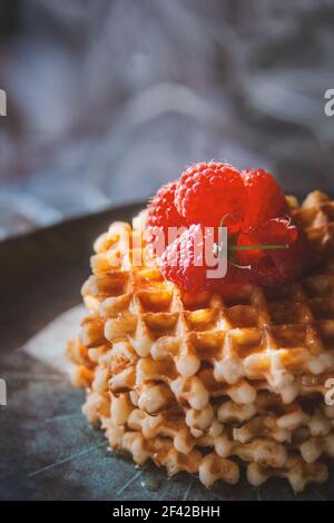 Cialde viennesi e lamponi. Vista ravvicinata. I lamponi maturi e succosi si trovano sui waffle. Spazio di copia. Foto Stock