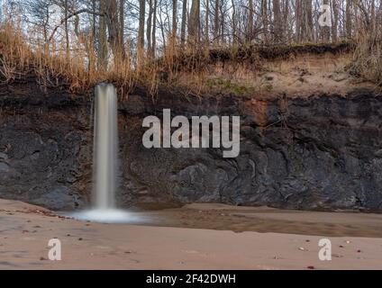 la cascata sulla riva scorre da un piccolo fiume nella foresta e scorre in acqua di mare lungo la sabbia leggera della spiaggia Foto Stock