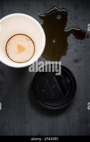 Caffè versato con tazza di caffè di carta vuota e coperchio Sfondo nero Foto Stock