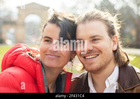 Una giovane coppia in un parco godendo la giornata di sole Foto Stock