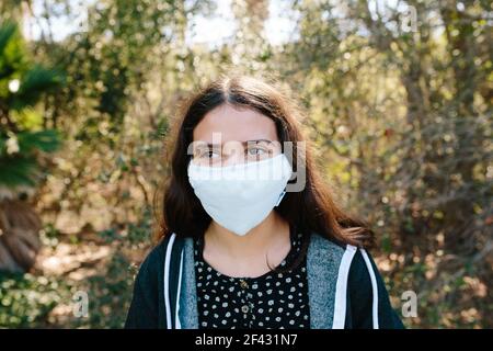 Giovane ragazza teen fuori sorride sotto una maschera facciale Foto Stock