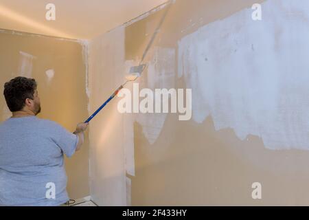 Eseguire l'adescamento con un rullo di vernice e riparare la parete dopo l'applicazione di intonaco per lavori interni Foto Stock