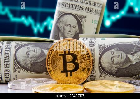 Calgary, Alberta, Canada. 12 marzo 2021. Un Bitcoin con la valuta degli Stati Uniti con le tabelle del mercato azionario di finanze sullo sfondo. Foto Stock