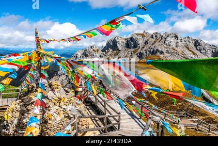 Vista sulla vetta del monte Shika nel mezzo di molti tibetani colorati Bandiere buddiste di preghiera e cielo blu in Cina Shangri-la Yunnan Foto Stock