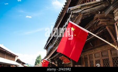 Bandiera cinese appesa su un'antica casa di legno e blu Cielo con spazio copia nel centro storico di Dali Yunnan Cina Foto Stock