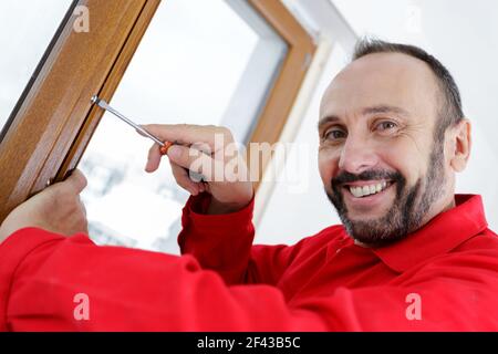 felice uomo che installa le tende con il cacciavite Foto Stock