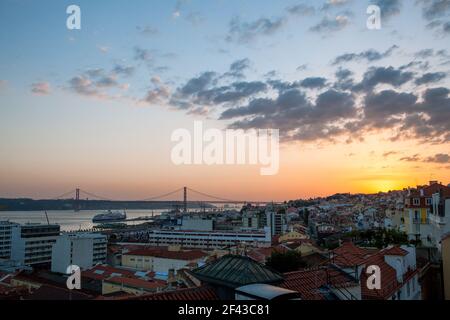 Splendido tramonto sullo skyline di Lisbona e sul suo iconico Ponte de 25 Abril che attraversa il fiume Tago, Portogallo. Foto Stock