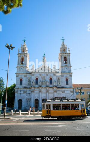 L'iconico tram giallo 28 passa di fronte alla Basilica da Estrela, la storica chiesa neoclassica situata nel centro di Lisbona, Portogallo. Foto Stock