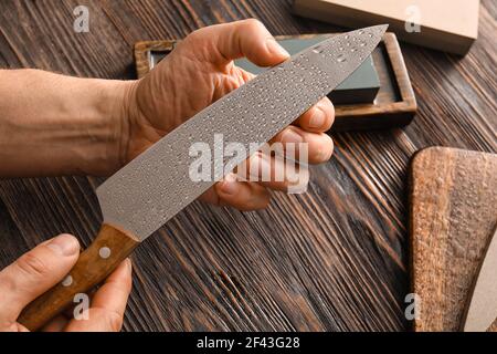 Mano maschio con coltello su fondo di legno, primo piano Foto Stock