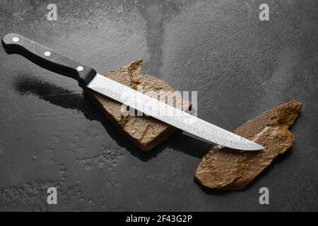 Coltello con pietre per affilatura su sfondo scuro Foto Stock