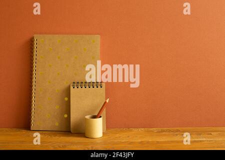 Notebook e matita colorata su scrivania in legno. Sfondo marrone Foto Stock