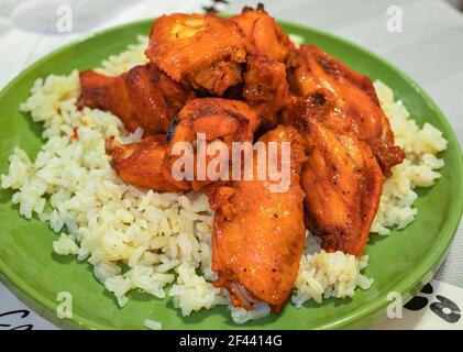 Ali di pollo speziate alla griglia con riso marrone bianco sul piatto verde. Cibo fatto in casa, cibo sano e gustoso. Foto Stock