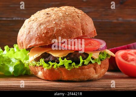 Hamburger fatto in casa con cotoletta, insalata, cipolla, pomodoro e formaggio. Cheeseburger, hamburger. Primo piano di hamburger fatti in casa Foto Stock