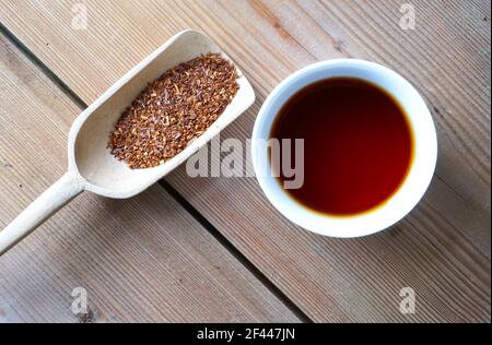 Rosso cespuglio rooibos tè sciolto su paletta di legno e cup africa prodotto naturale Foto Stock