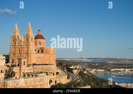 Cielo blu e oceano intorno alla chiesa parrocchiale di Mellieha, Malta in un giorno di autunno. Foto Stock