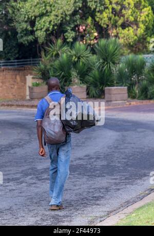 Johannesburg, Sud Africa - uomo senza dimora non identificato cammina per la strada portando tutti i suoi effetti personali Foto Stock