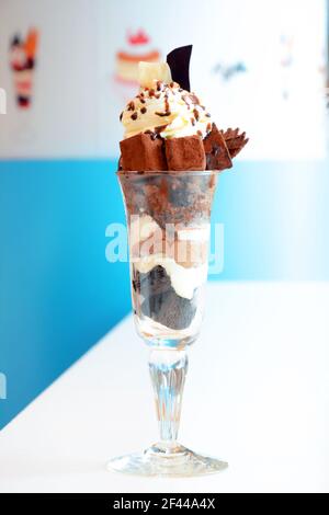 Delizioso gelato al cioccolato nel bicchiere con piccola cioccolata bar e panna montata sulla parte superiore Foto Stock