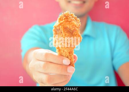 Un uomo che dà gamba di pollo fritta o bastone di pollo Foto Stock