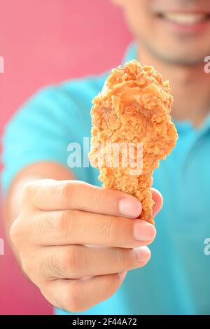 Un uomo che dà gamba di pollo fritta o bastone di pollo Foto Stock