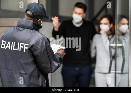 Bailiff debt Collector a Door in Mask Foto Stock