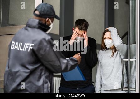 Bailiff debt Collector a Door in Mask Foto Stock