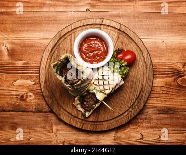 Carne tritata avvolta con pane di lavasino su fondo di legno Foto Stock