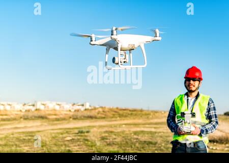 Un fuoco selettivo di un drone operato da un caucasico lavoratore di costruzione in un cantiere Foto Stock
