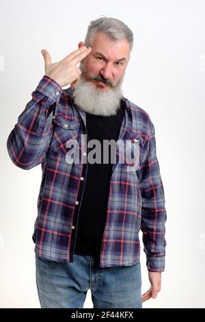 Studio ritratto di uomo maturo bearded che punta il movimento della pistola del dito alla testa. Gesto di suicidio. Isolato su sfondo bianco. Foto Stock