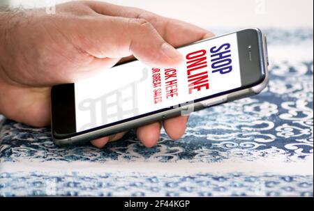mano maschile facendo shopping online cliccando sullo schermo del suo cellulare. Tecnologia e commercio elettronico. Acquistare oggetti Foto Stock