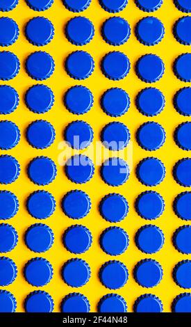 Modello di molti tappi blu in metallo su sfondo giallo. Foto Stock