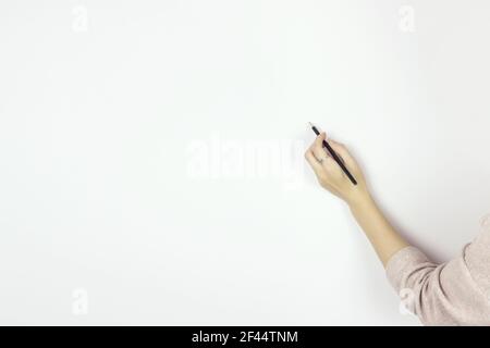 Mano che tiene la matita di legno che inizia a disegnare su bianco muro, spazio di copia Foto Stock