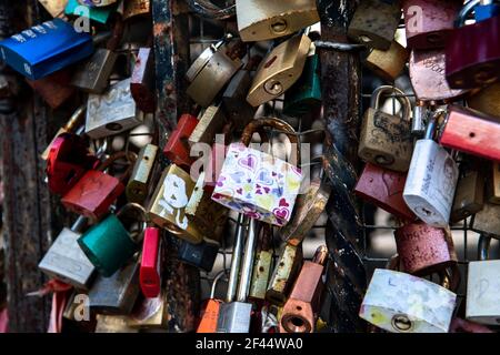 Colorati lucchetti d'amore attaccati su Iron Fence Foto Stock