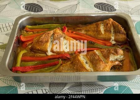 Pesce rosso arrosto fatto in casa con peperoni rossi, verdi e cipolle pronti a mangiare. Foto Stock